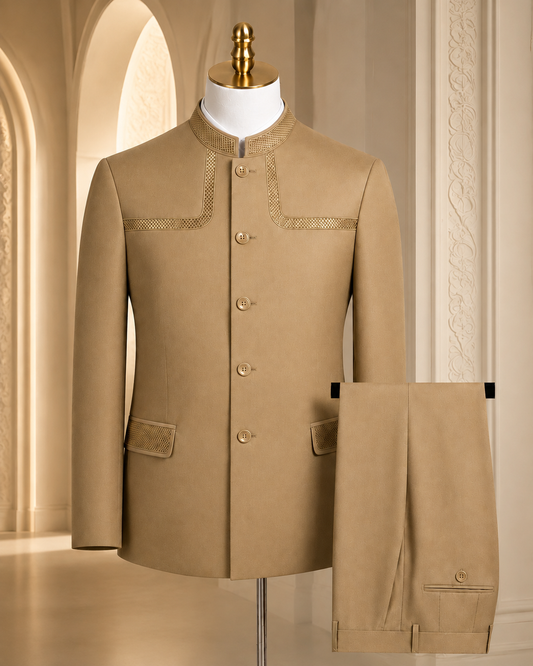 A beige men's traditional jacket displayed on a mannequin, paired with matching trousers hanging beside it. The jacket has a mandarin collar, front buttons, decorative embroidered detailing on the chest, and flap pockets.