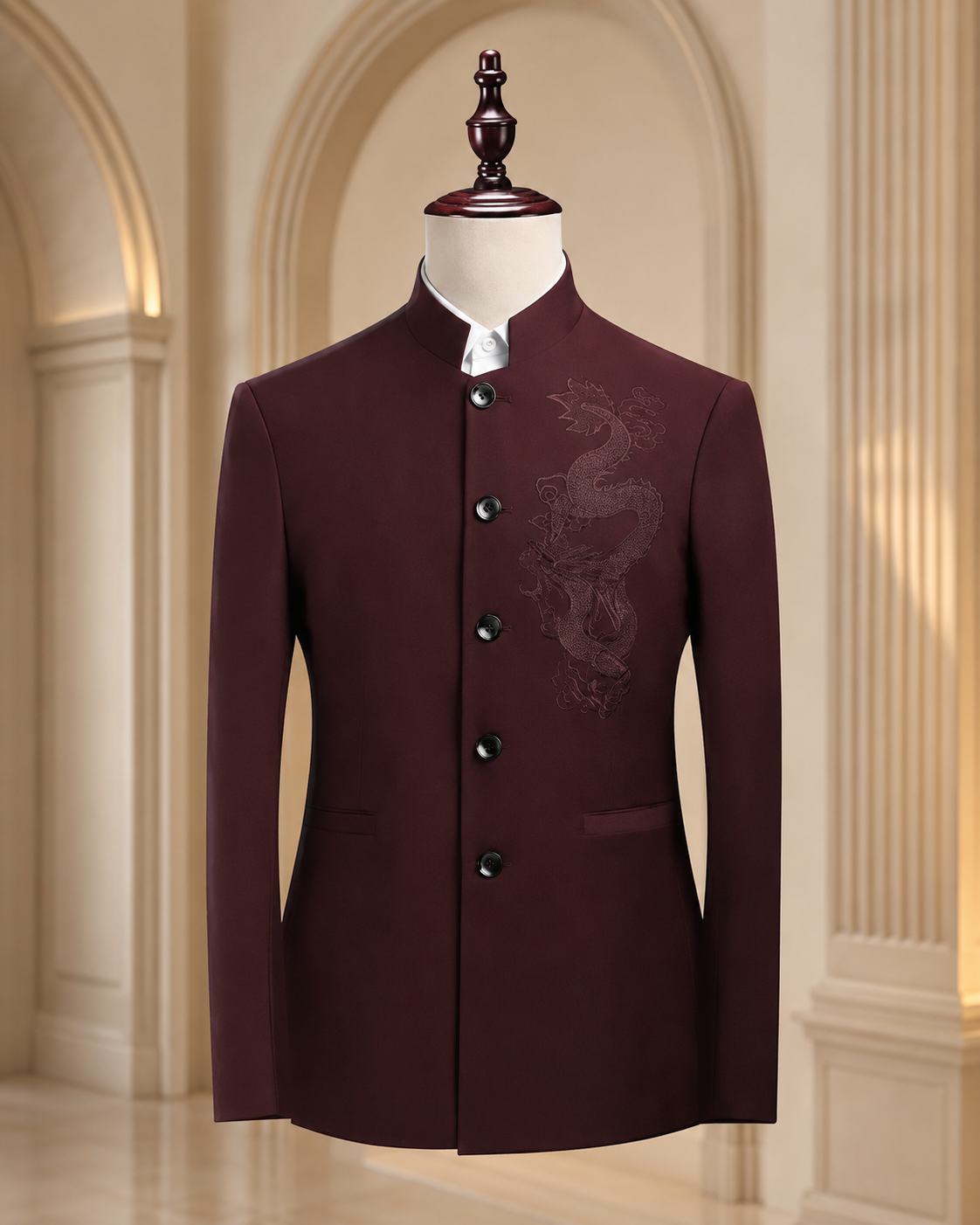 A dark maroon men's jacket with a mandarin collar and subtle dragon embroidery on the chest, displayed on a mannequin in an elegant indoor setting with arched columns.