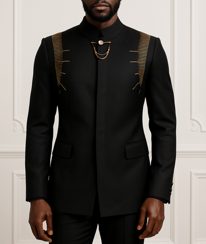 Man wearing a black suit with gold accents against a white wall