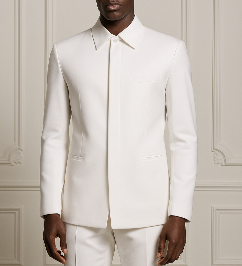 Man wearing a white suit standing against a light-colored paneled wall.